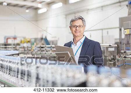 Stock Image - Supervisor smiling in bottling plant. Fotosearch