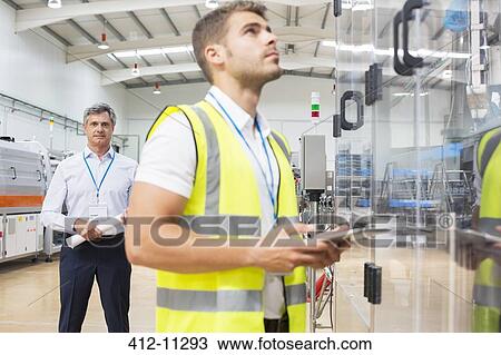 Supervisor watching worker in factory View Large Photo Image Stock Image - Supervisor watching worker in factory. Fotosearch