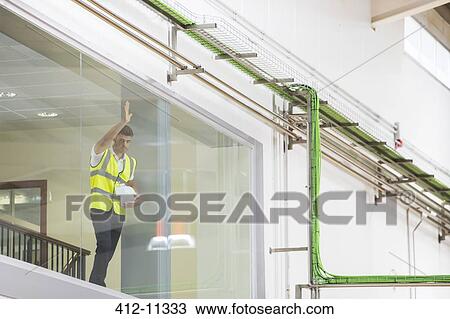Worker leaning on observation window in factory View Large Photo Image Stock Image - Worker leaning on observation window in factory. Fotosearch