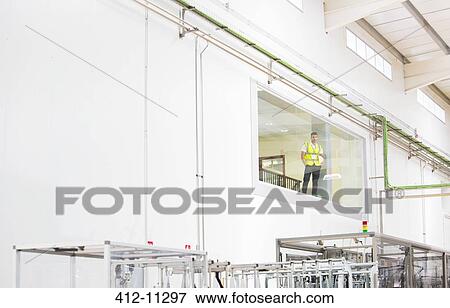 Worker looking out glass window in warehouse View Large Photo Image Stock Photo - Worker looking out glass window in warehouse. Fotosearch