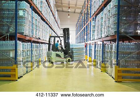 Stock Photo - Worker moving pallets with forklift in warehouse. Fotosearch