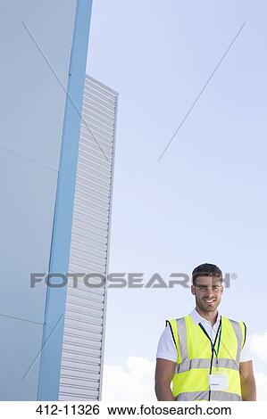 Stock Photograph - Worker smiling below highrise buildings. Fotosearch