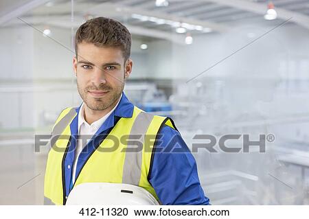 Worker smiling by window in factory View Large Photo Image Stock Image - Worker smiling by window in factory. Fotosearch