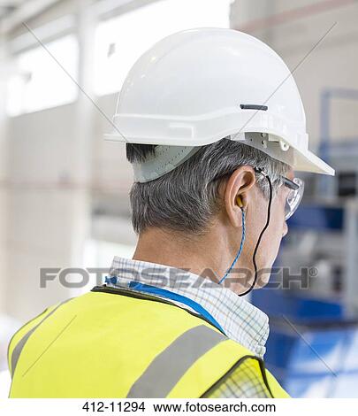 Picture - Worker wearing hard hat and ear plugs. Fotosearch