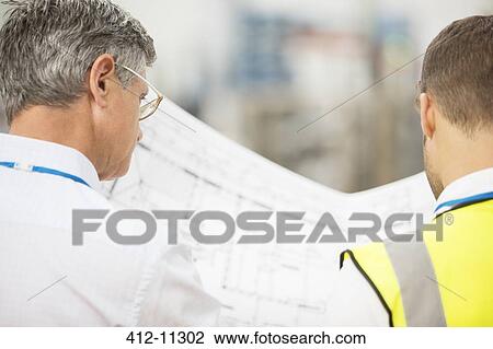 Workers reading blueprints in warehouse View Large Photo Image Stock Image - Workers reading blueprints in warehouse. Fotosearch