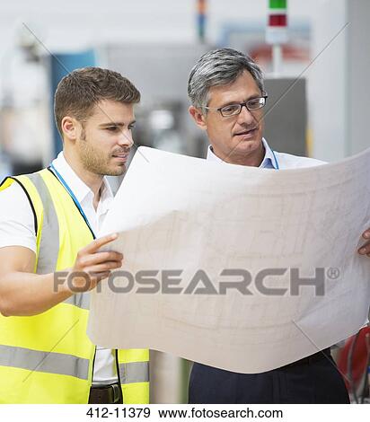 Stock Photo - Workers viewing blueprints in factory. Fotosearch
