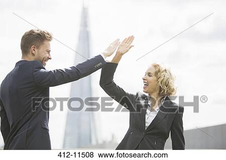Stock Photo - Business people high fiving outdoors. Fotosearch