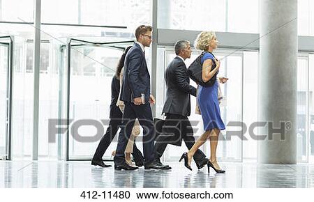 Stock Image - Business people walking in office lobby. Fotosearch
