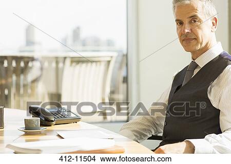 Picture - Businessman sitting at desk in office. Fotosearch