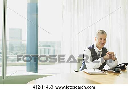 Businessman smiling at desk in office View Large Photo Image Stock Image - Businessman smiling at desk in office. Fotosearch