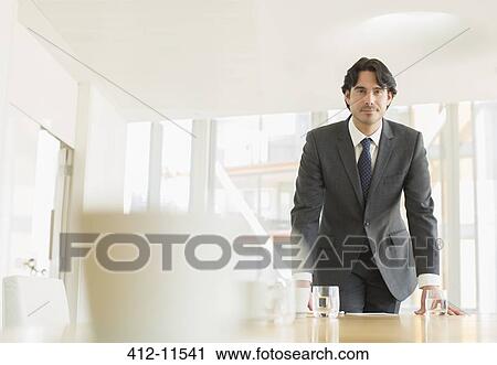Stock Image - Businessman standing at conference table. Fotosearch