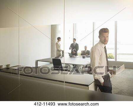 Businessman standing in office View Large Photo Image Stock Image - Businessman standing in office. Fotosearch