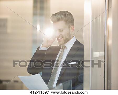 Stock Photo - Businessman talking on cell phone in office. Fotosearch