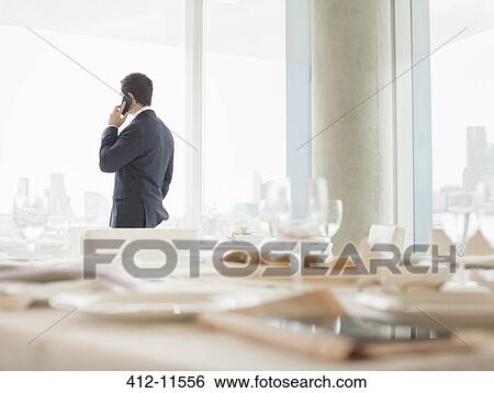 Stock Photograph - Businessman talking on cell phone in restaurant. Fotosearch