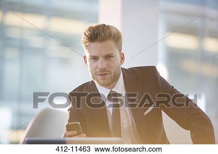 Stock Image - Businessman using cell phone in office. Fotosearch