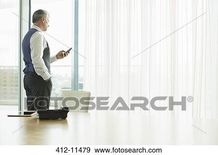 Stock Photo - Businessman using cell phone in office. Fotosearch