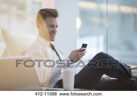 Stock Photo - Businessman using cell phone in office. Fotosearch