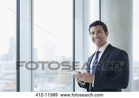 Businessman using cell phone in office View Large Photo Image Stock Photo - Businessman using cell phone in office. Fotosearch
