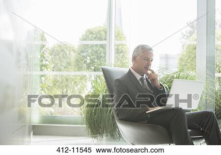 Businessman using laptop in lobby View Large Photo Image Stock Photography - Businessman using laptop in lobby. Fotosearch