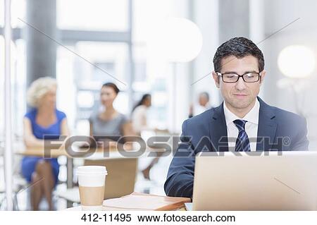 Stock Photography - Businessman working at laptop in cafe. Fotosearch