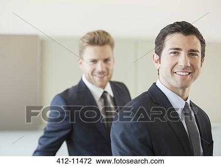Stock Image - Businessmen smiling in office. Fotosearch