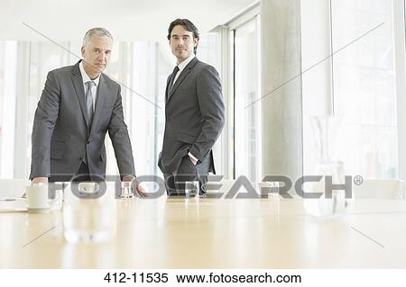 Stock Photography - Businessmen standing at conference table. Fotosearch