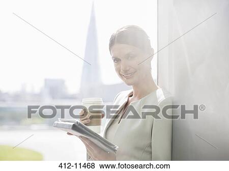 Stock Photo - Businesswoman drinking cup of coffee in office. Fotosearch