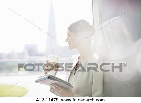 Businesswoman enjoying cup of coffee at window View Large Photo Image Stock Photo - Businesswoman enjoying cup of coffee at window. Fotosearch