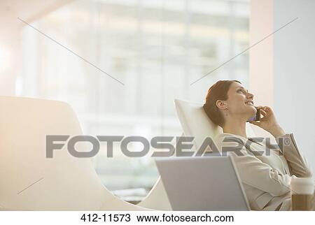 Businesswoman talking on cell phone in office View Large Photo Image Stock Image - Businesswoman talking on cell phone in office. Fotosearch