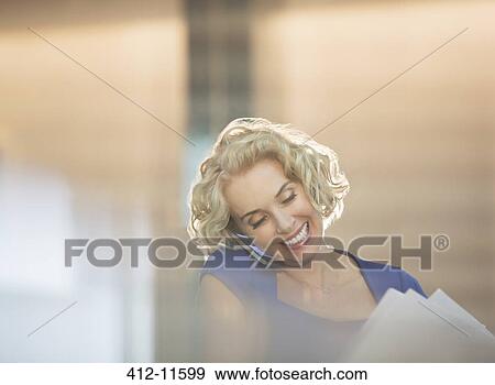 Stock Photo - Businesswoman talking on cell phone in office. Fotosearch