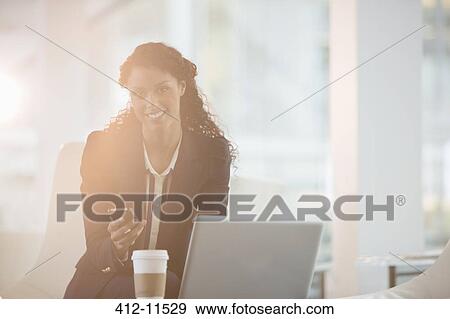 Stock Photo - Businesswoman using cell phone in office. Fotosearch