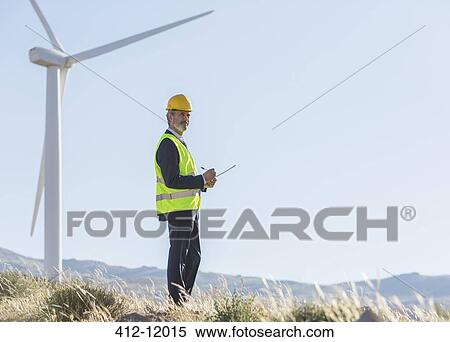 Businessman examining wind turbines in rural landscape View Large Photo Image Stock Photography - Businessman examining wind turbines in rural landscape. Fotosearch