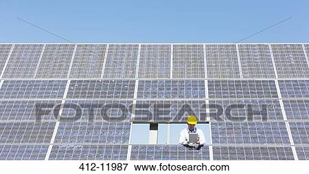 Scientist examining solar panel in rural landscape View Large Photo Image Stock Photo - Scientist examining solar panel in rural landscape. Fotosearch