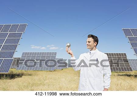Scientist examining sphere by solar panels View Large Photo Image Stock Photo - Scientist examining sphere by solar panels. Fotosearch