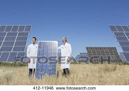 Scientists holding solar panel in rural landscape View Large Photo Image Stock Photograph - Scientists holding solar panel in rural landscape. Fotosearch