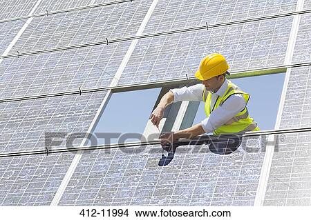 Worker examining solar panel in rural landscape View Large Photo Image Picture - Worker examining solar panel in rural landscape. Fotosearch