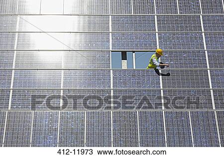 Worker examining solar panel in rural landscape View Large Photo Image Stock Image - Worker examining solar panel in rural landscape. Fotosearch
