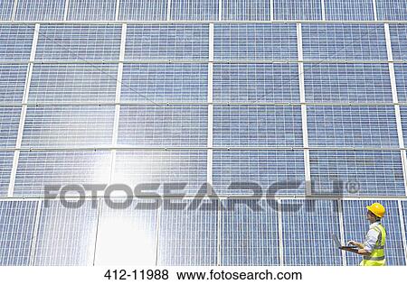 Worker examining solar panel in rural landscape View Large Photo Image Stock Photo - Worker examining solar panel in rural landscape. Fotosearch