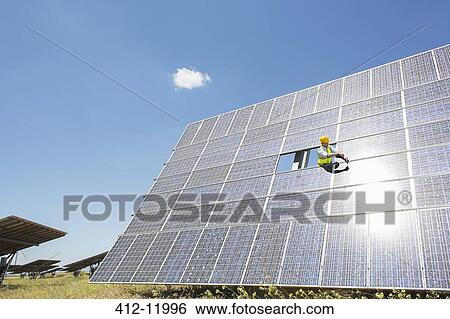 Worker examining solar panel in rural landscape View Large Photo Image Stock Photograph - Worker examining solar panel in rural landscape. Fotosearch