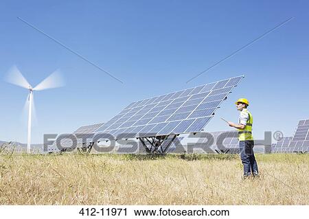 Worker examining solar panels in rural landscape View Large Photo Image Stock Image - Worker examining solar panels in rural landscape. Fotosearch
