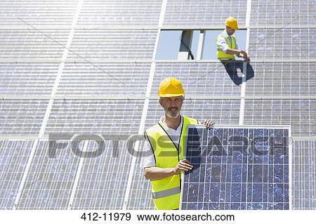 Worker holding solar panel in rural landscape View Large Photo Image Stock Photo - Worker holding solar panel in rural landscape. Fotosearch