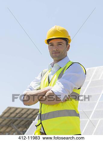 Worker standing by solar panels in rural landscape View Large Photo Image Stock Image - Worker standing by solar panels in rural landscape. Fotosearch