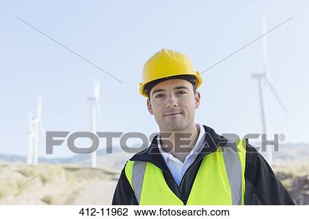 Worker standing by wind turbines in rural landscape View Large Photo Image Stock Image - Worker standing by wind turbines in rural landscape. Fotosearch