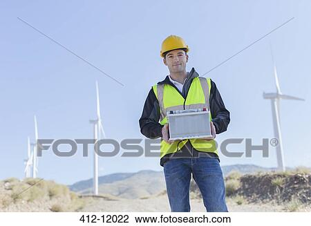 Worker standing by wind turbines in rural landscape View Large Photo Image Stock Image - Worker standing by wind turbines in rural landscape. Fotosearch
