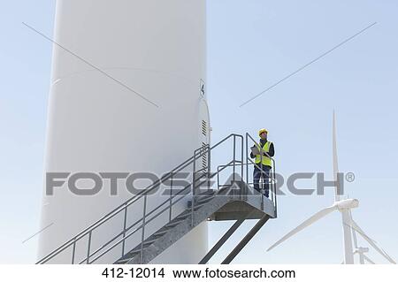 Worker standing on wind turbine View Large Photo Image Picture - Worker standing on wind turbine. Fotosearch