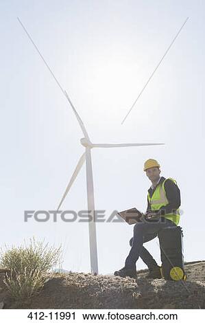 Worker using laptop by wind turbine in rural landscape View Large Photo Image Stock Image - Worker using laptop by wind turbine in rural landscape. Fotosearch
