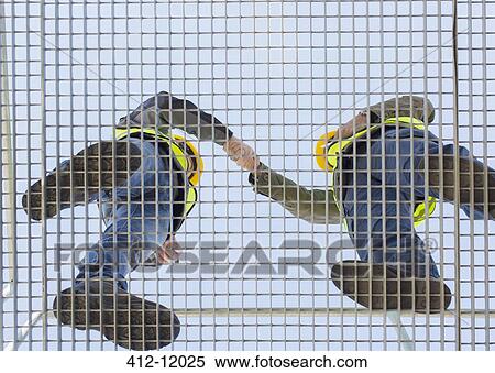 Workers shaking hands on grating View Large Photo Image Stock Photography - Workers shaking hands on grating. Fotosearch