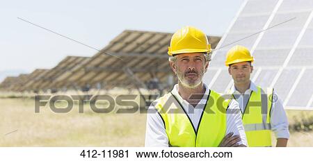 Workers standing by solar panels in rural landscape View Large Photo Image Stock Image - Workers standing by solar panels in rural landscape. Fotosearch
