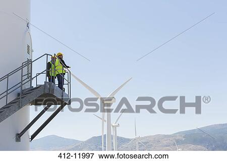 Workers standing on wind turbine in rural landscape View Large Photo Image Stock Photo - Workers standing on wind turbine in rural landscape. Fotosearch