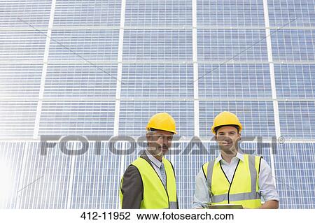 Workers standing under shade by solar panel View Large Photo Image Stock Image - Workers standing under shade by solar panel. Fotosearch